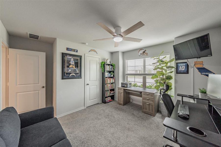 Carpeted room with a ceiling fan, two panel doors, and a window with horizontal blinds