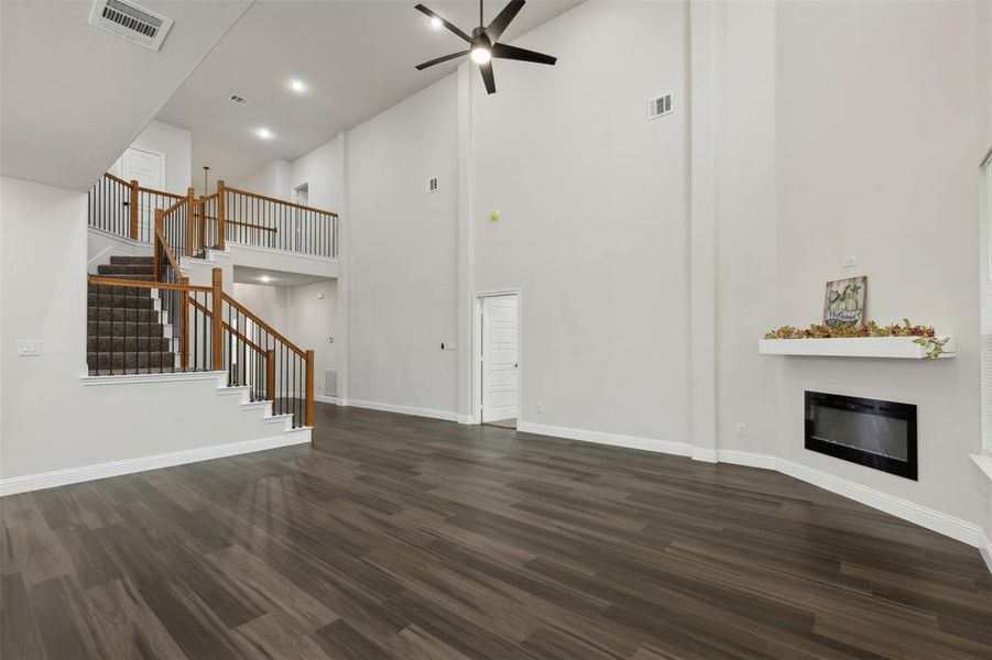 Unfurnished living room featuring dark hardwood / wood-style flooring, high vaulted ceiling, and ceiling fan