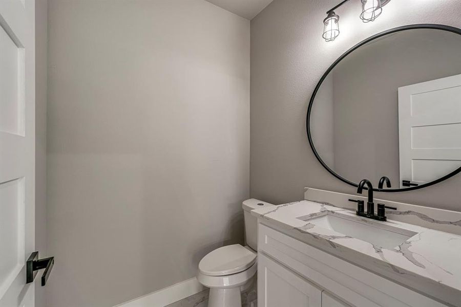 Bathroom featuring vanity, toilet, baseboards, and marble finish floor