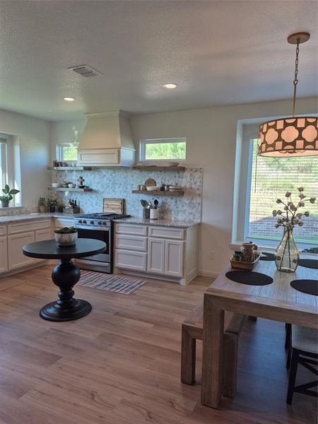 Kitchen featuring white cabinets, open shelves, extractor fan, a textured ceiling, and light stone counters