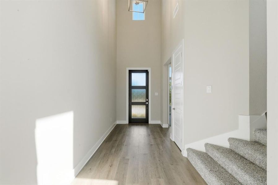 Entrance foyer featuring stairway, a towering ceiling, and light wood finished floors