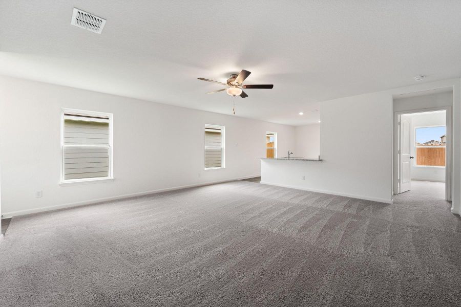 A spacious living area with plush carpeting flows into a contemporary kitchen, ideal for entertaining.