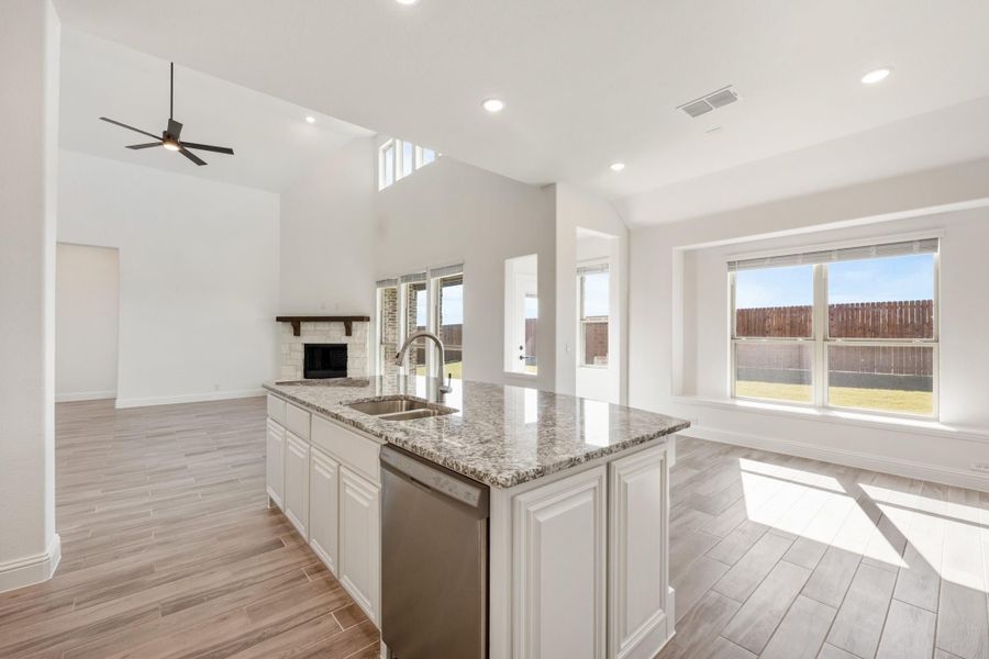 Kitchen island with granite countertop and sink, open to living area with fireplace and high ceilings Kitchen island with granite countertop and sink, open to living area with fireplace and high ceilings