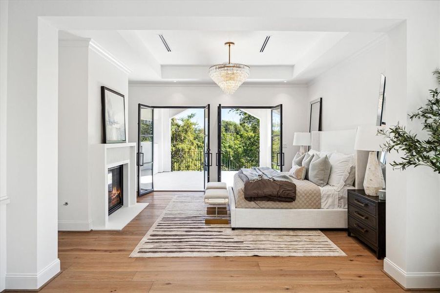 This luxurious primary retreat features a cozy breakfast bar and a custom fluted cast stone fireplace, creating an intimate and inviting atmosphere. Two sets of Durango doors open to a private balcony, allowing for a seamless indoor- outdoor connection and stunning views.