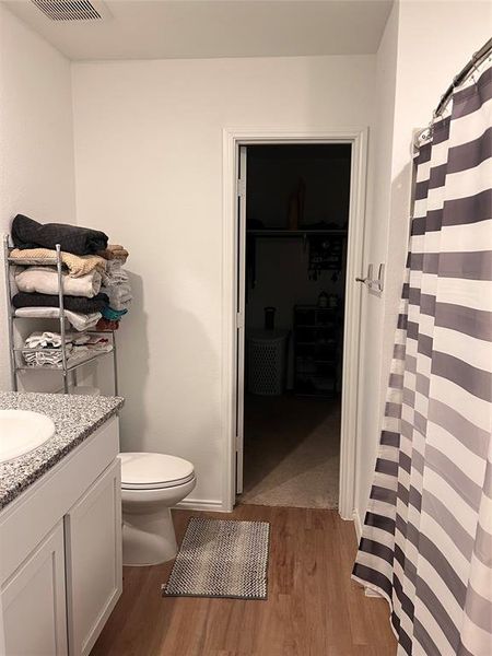 Full bath featuring curtained shower, dark wood-style flooring, vanity, and a spacious closet Full bath featuring curtained shower, dark wood-style flooring, vanity, and a spacious closet