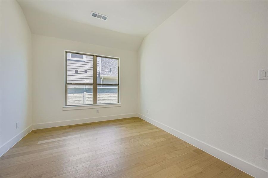 Empty room with light wood finished floors and vaulted ceiling Empty room with light wood finished floors and vaulted ceiling
