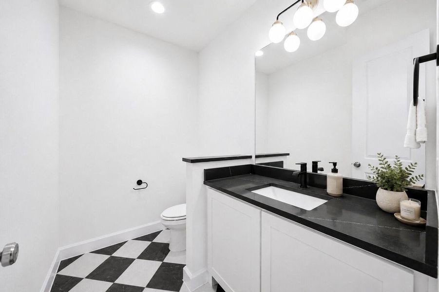 Designer-inspired powder room featuring striking black-and-white flooring, sleek quartz countertops, modern matte black fixtures, and clean contemporary finishes