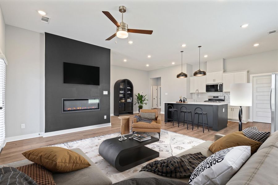 Living room featuring a fireplace, light wood-type flooring, ceiling fan, arched walkways, and recessed lighting