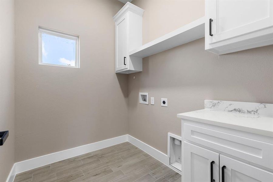 Clothes washing area with cabinets, washer hookup, light hardwood / wood-style floors, and electric dryer hookup