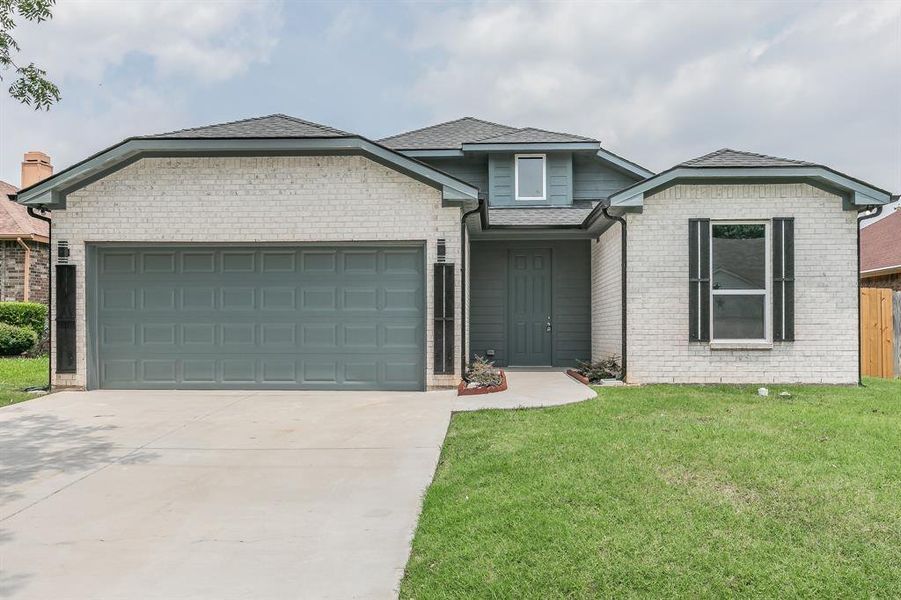 View of front of house with a garage and a front lawn