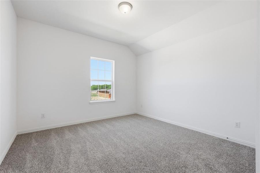 Carpeted spare room with baseboards and lofted ceiling
