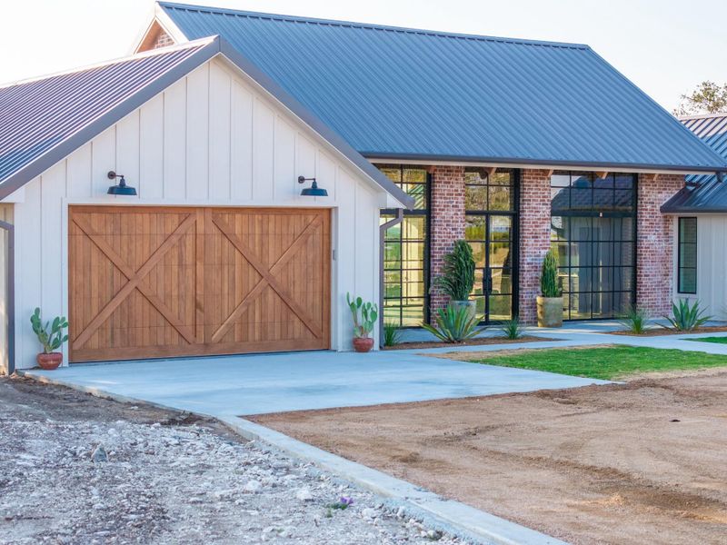 View of front of property with a metal roof, board and batten siding, and brick siding