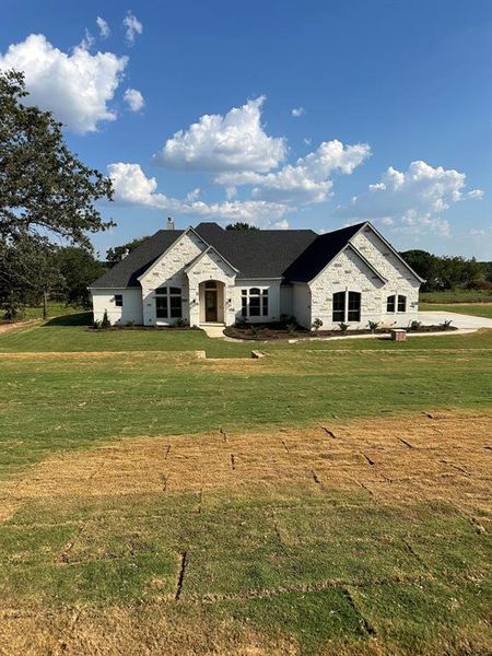 French provincial home with a front lawn, stone siding, and a chimney