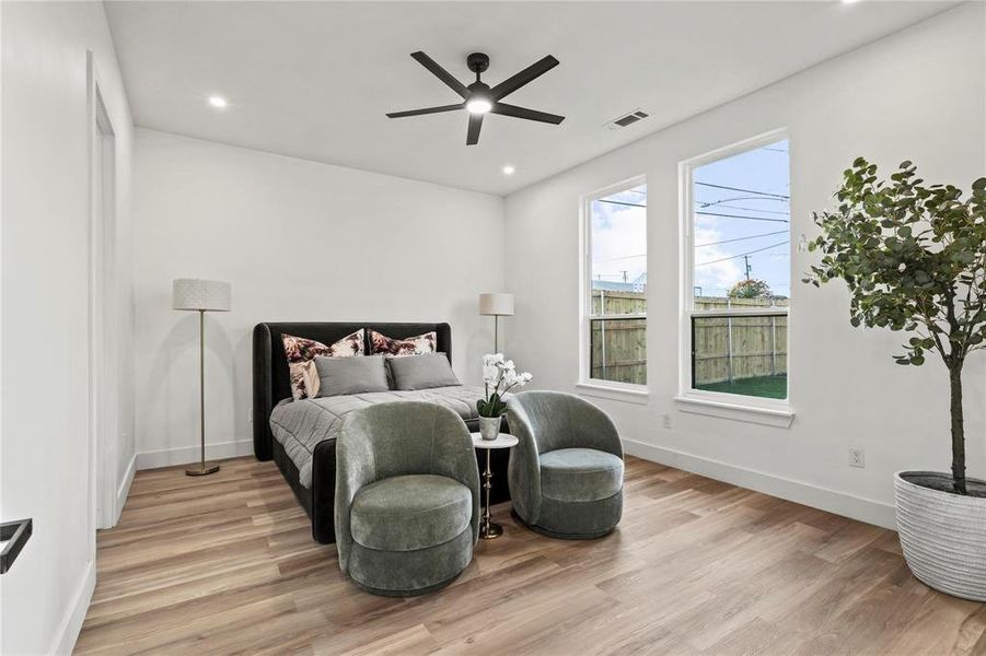 Spacious room featuring wood-finish flooring, two tall windows, a ceiling fan, recessed lighting, and white walls