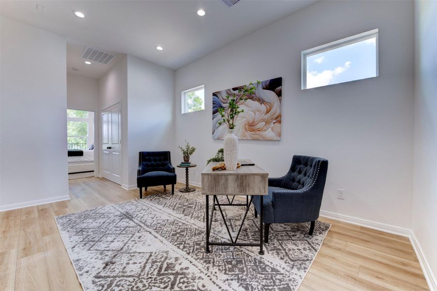 Open flex room with hardwood floors, high ceilings, recessed lighting, dual clerestory windows, and direct sightline to secondary bedroom hallway. Double doors visible at rear.