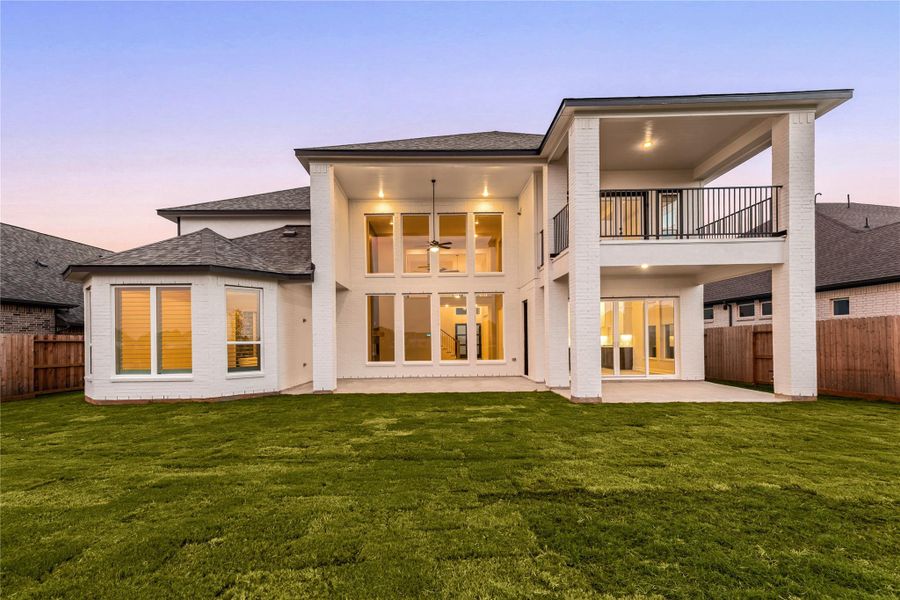 Magnificent rear exterior view showcasing the grand scale and premium outdoor living spaces of this luxury home. The striking white brick facade is beautifully complemented by a towering wall of multi-tier family room windows. This expansive layout features a massive covered main patio, a secondary covered lounge area off the breakfast room slider, and an elegant second-story balcony. Complete with a huge, pool-ready green lawn, this backyard oasis is built for spectacular outdoor entertaining. Magnificent rear exterior view showcasing the grand scale and premium outdoor living spaces of this luxury home. The striking white brick facade is beautifully complemented by a towering wall of multi-tier family room windows. This expansive layout features a massive covered main patio, a secondary covered lounge area off the breakfast room slider, and an elegant second-story balcony. Complete with a huge, pool-ready green lawn, this backyard oasis is built for spectacular outdoor entertaining.