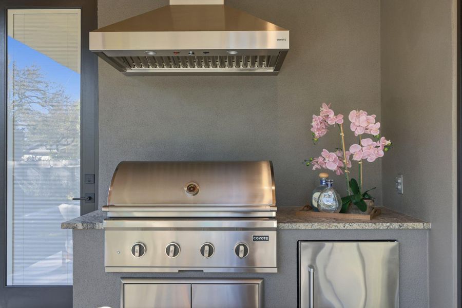 Detailed view of range hood, stainless steel refrigerator, and stucco siding