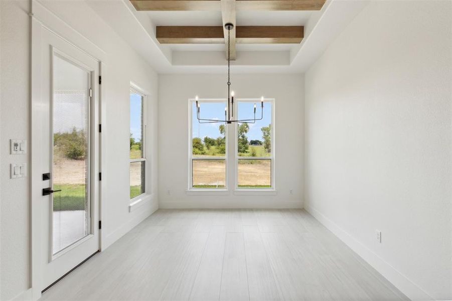 Unfurnished dining area with light hardwood / wood-style floors, beam ceiling, coffered ceiling, and a chandelier