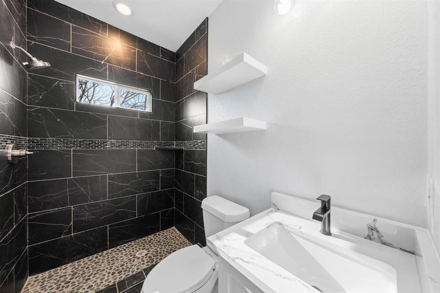 Bathroom featuring tiled shower and vanity
