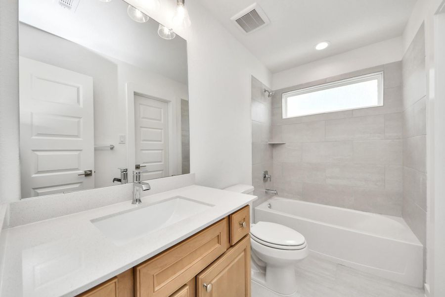 Secondary bath features tile flooring, bath/shower combo with tile surround, light stained wood cabinets, beautiful light countertop. Secondary bath features tile flooring, bath/shower combo with tile surround, light stained wood cabinets, beautiful light countertop.