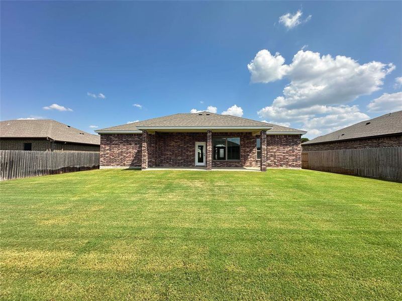 Back of property with a patio, a fenced backyard, brick siding, and roof with shingles Back of property with a patio, a fenced backyard, brick siding, and roof with shingles