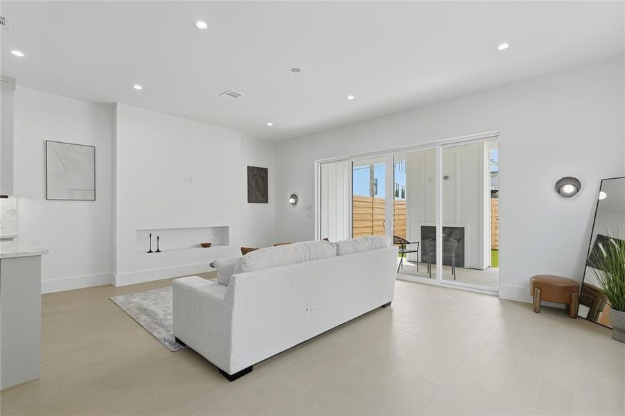 Open-concept living area featuring light-toned flooring, recessed lighting, and a built-in wall niche