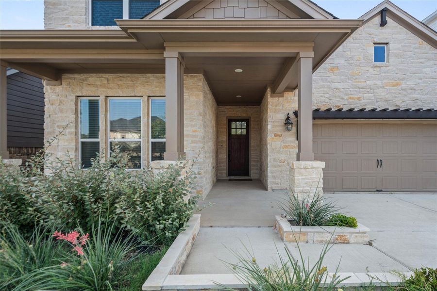 Stone masonry accents and a covered entryway establish an inviting transition from the driveway.