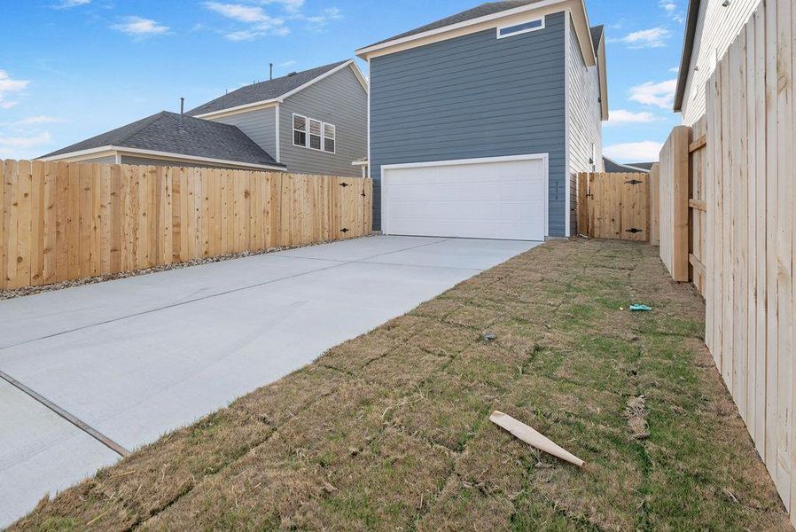 Rear view of property with a gate, a garage, and concrete driveway