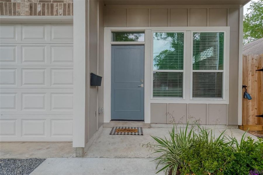 Covered front porch with recessed lighting. Front yard has green space.