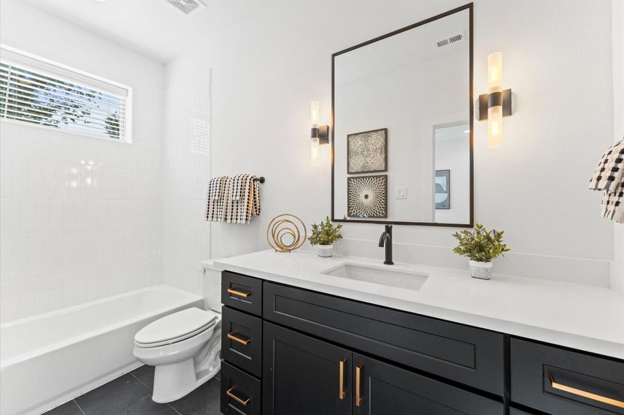 Spacious open-concept living area with modern furnishings, sleek black accents, and abundant natural light, seamlessly connecting to a stylish kitchen and dining space.