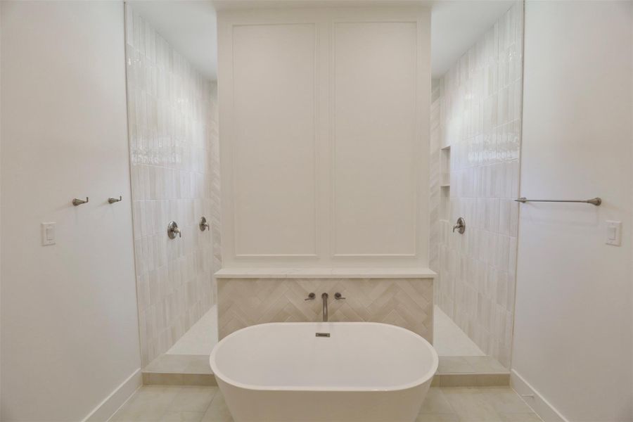 The spacious freestanding tub is paired with a sleek quartz ledge to hold your essentials, while the wall above, accented in harmony with the tile and vanity, serves as a masterful showcase of craftsmanship creating a serene, spa-like experience. The spacious freestanding tub is paired with a sleek quartz ledge to hold your essentials, while the wall above, accented in harmony with the tile and vanity, serves as a masterful showcase of craftsmanship creating a serene, spa-like experience.