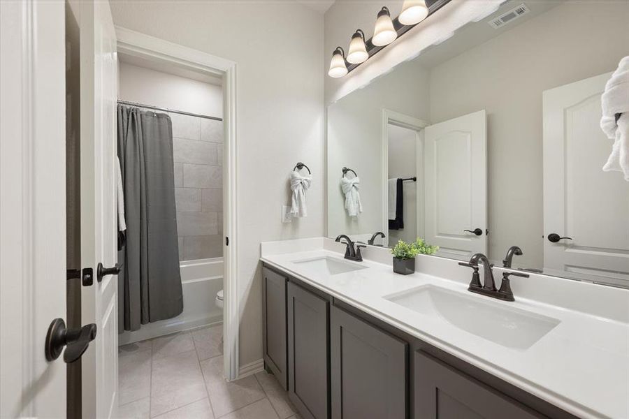 Full bathroom upstairs includes a large vanity with dual undermount sinks, bronze fixtures and hardware, tiled flooring and a separate tile surround bath and elongated toilet.