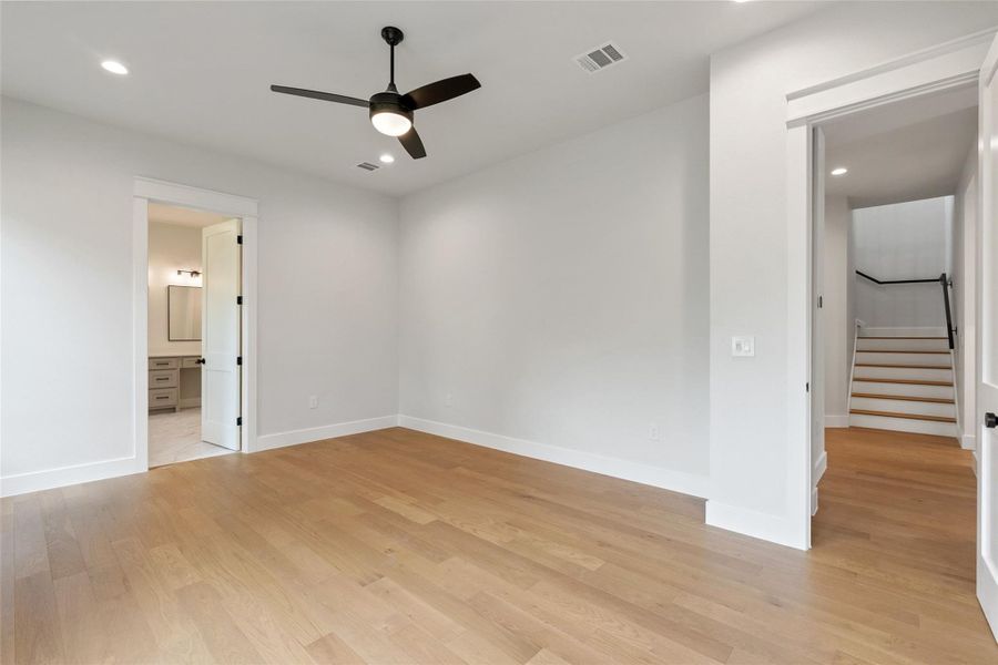 Blonde hardwood floors grace this naturally illuminated primary bedroom, offering a serene retreat with an en-suite bath.