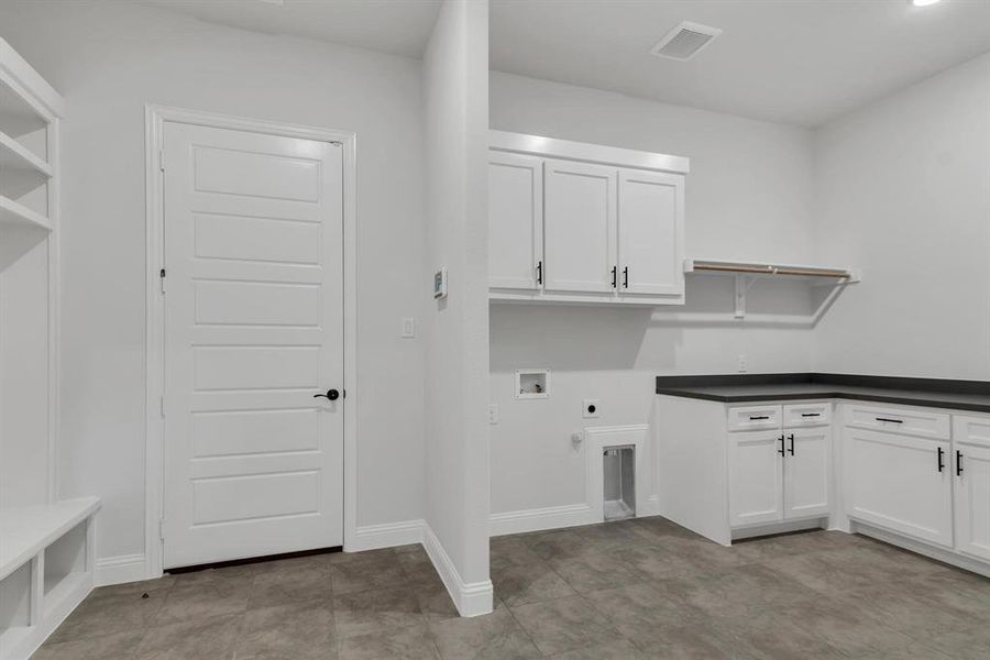 Clothes washing area with cabinets, hookup for a washing machine, hookup for an electric dryer, and light tile patterned floors