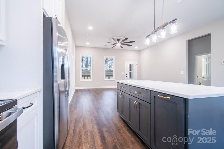 Open-concept kitchen featuring a large quartz island, contrasting cabinetry, and stainless steel appliances.
