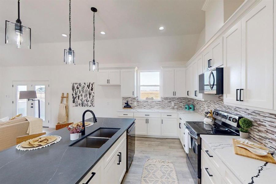 Kitchen with sink, white cabinets, decorative light fixtures, and appliances with stainless steel finishes