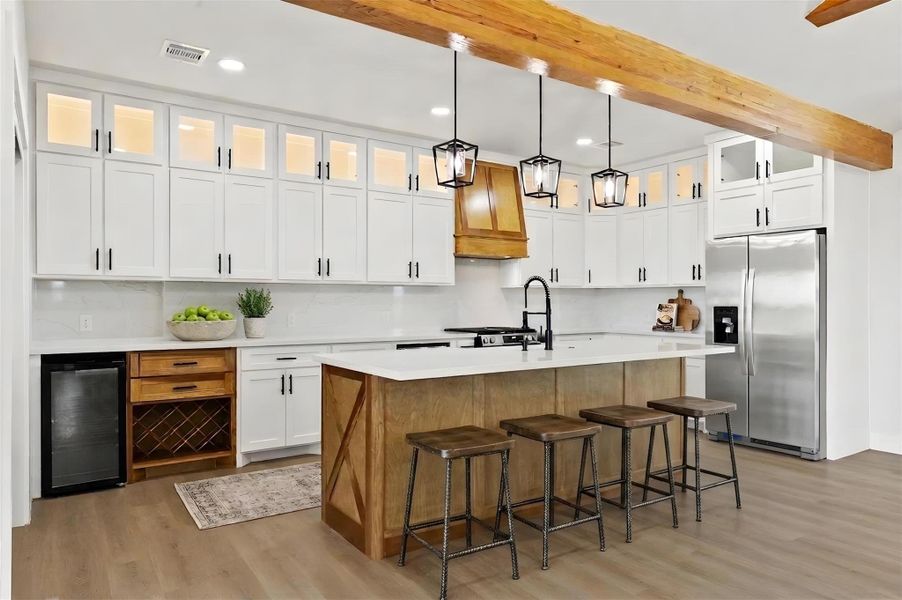 The kitchen blends style and function with quartz countertops, a wood island with an apron-front farmhouse sink, beverage refrigerator, wine storage, under-counter microwave, lighted glass-front cabinetry, and a large walk-in pantry. Virtually staged. Furniture and décor shown are for illustrative purposes only.