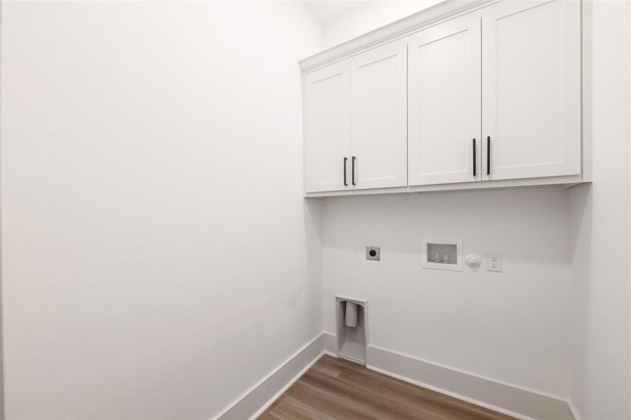 Laundry room with cabinet space, light wood-type flooring, electric dryer hookup, hookup for a washing machine, and hookup for a gas dryer