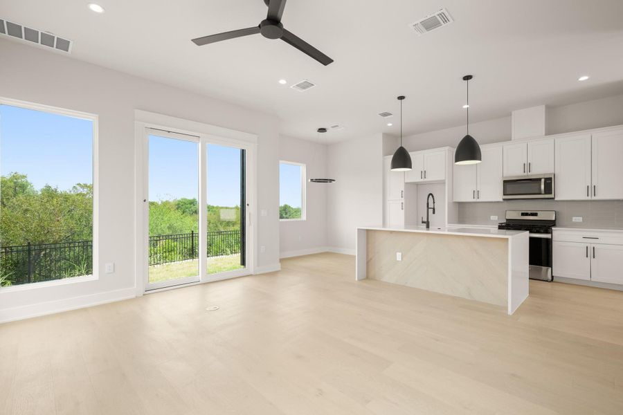 Kitchen with backsplash, an island with sink, stainless steel appliances, recessed lighting, and white cabinetry Kitchen with backsplash, an island with sink, stainless steel appliances, recessed lighting, and white cabinetry