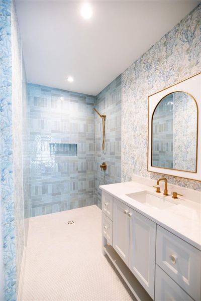 Bathroom featuring a tile shower, recessed lighting, and vanity