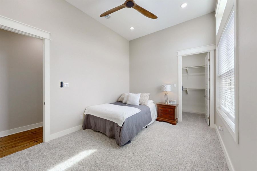 Light-filled room featuring a walk in closet, vaulted ceiling with a ceiling fan, recessed lighting, and soft beige carpeting