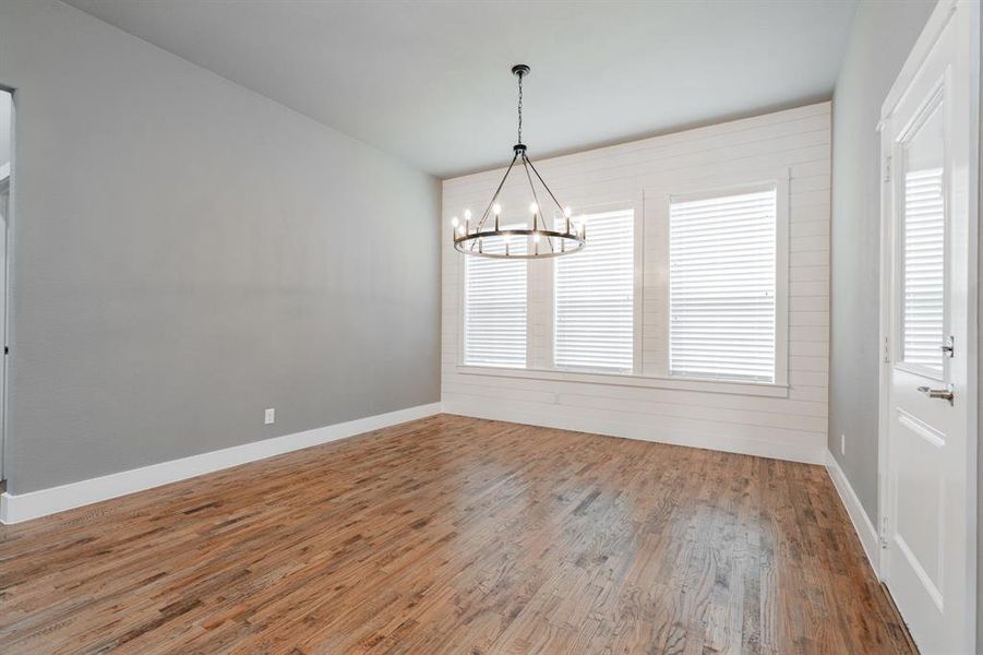 Unfurnished dining area with an inviting chandelier, baseboards, and wood finished floors Unfurnished dining area with an inviting chandelier, baseboards, and wood finished floors