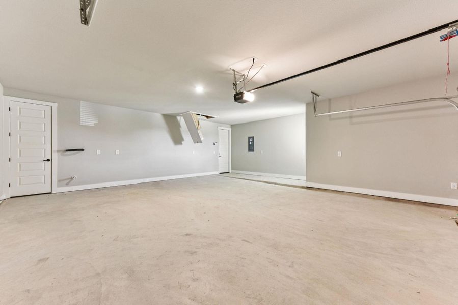 Garage featuring baseboards and electric panel
