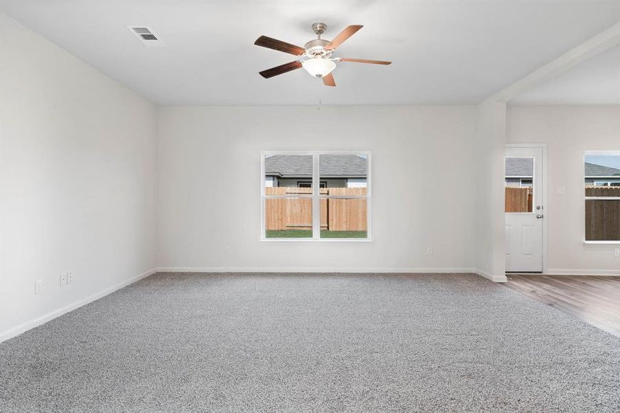 Carpeted spare room with a healthy amount of sunlight and ceiling fan