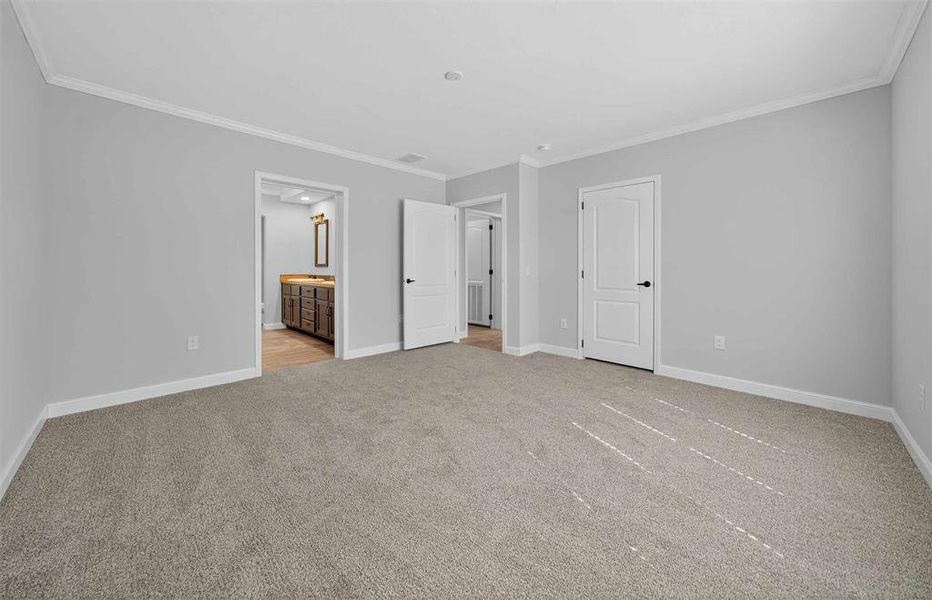 Unfurnished bedroom with ornamental molding, light carpet, and ensuite bath Unfurnished bedroom with ornamental molding, light carpet, and ensuite bath