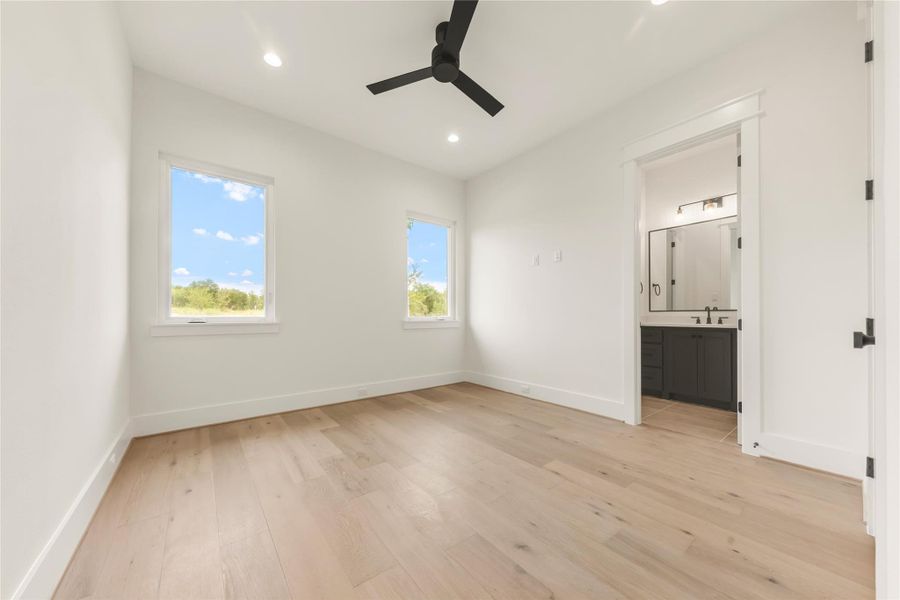 Unfurnished bedroom with light wood finished floors, ceiling fan, recessed lighting, and ensuite bath