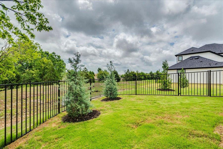 A well-maintained lawn and sturdy wrought iron fence define the property's perimeter.
