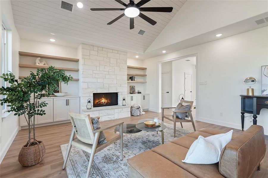 Living room with a stone fireplace, built in features, high vaulted ceiling, wood ceiling, and light wood-type flooring