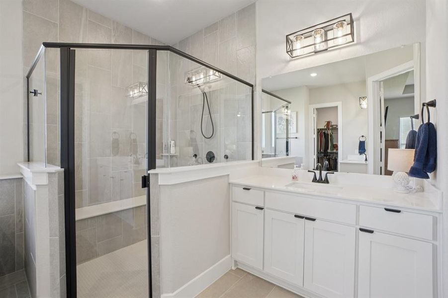 Primary bath with tiled shower, spa bath, separate vanities, and a spacious closet
