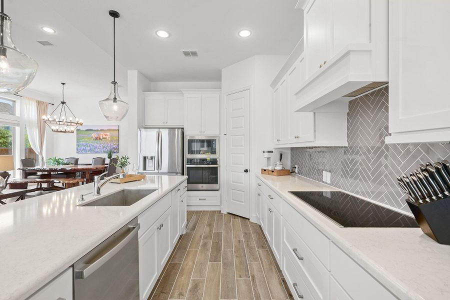Bright and modern kitchen with the open layout connecting to the breakfast area with elegant lighting and large windows, providing a spacious and inviting atmosphere.